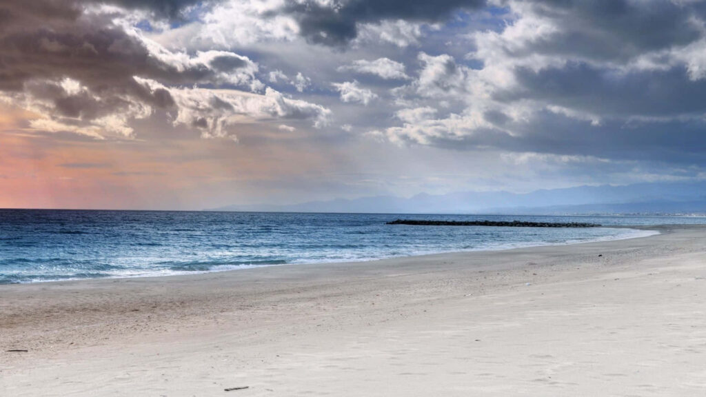 Serene Beach Wallpaper: Tranquil Shoreline & Dramatic Clouds