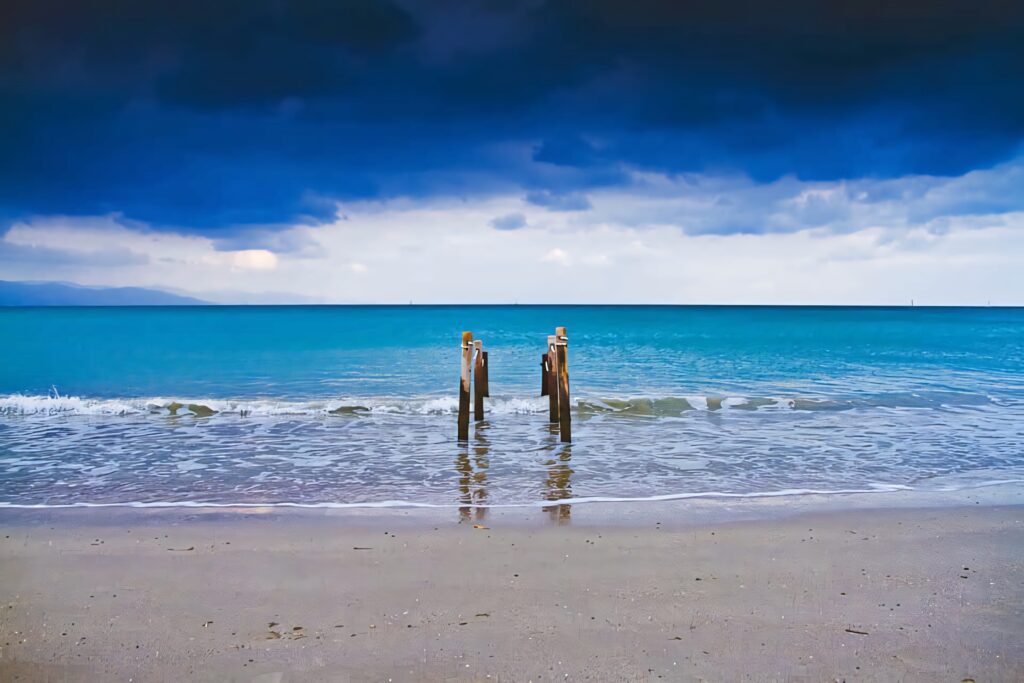 Serene Beach Wallpaper: Waves, Moody Sky & Rustic Wooden Posts