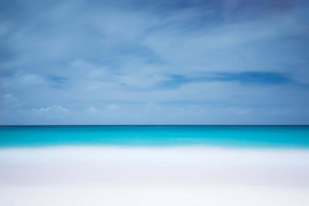 Serene Beach Wallpaper: Turquoise Waters & Soft Blue Sky Background