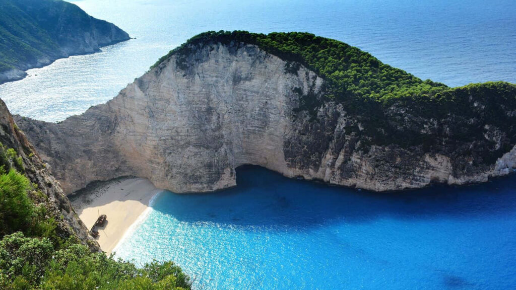 Serene Beach Wallpaper: Vibrant Waters & Towering Cliffs Background