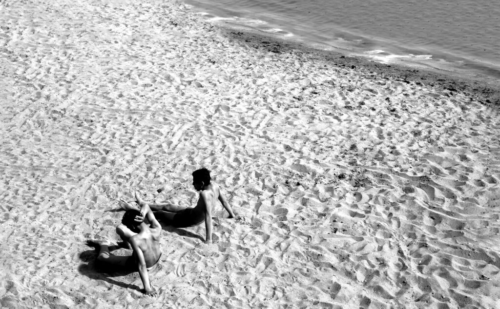 Serene Beach Vibe: Two People Relax by the Water's Edge Wallpaper