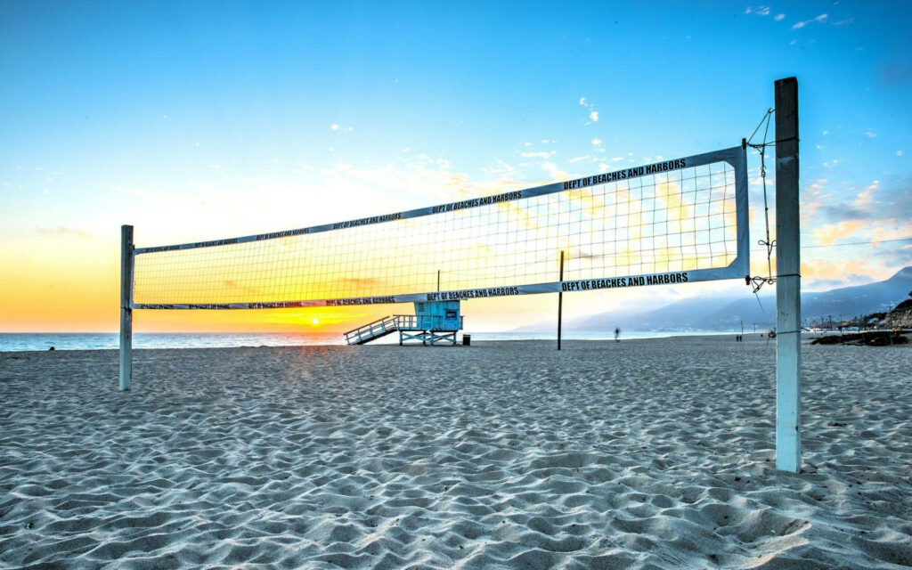 Serene Beach Volleyball Sunset Wallpaper with Lifeguard Post
