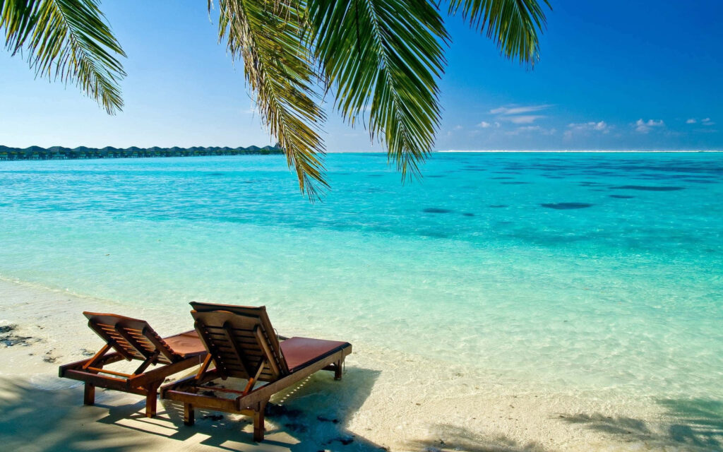 Relaxing Beach Scene: Wooden Chairs, White Sand & Turquoise Ocean Wallpaper