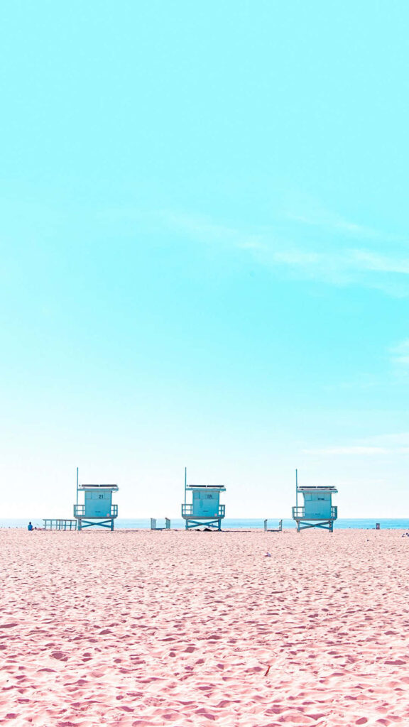 Serene Beachscape Wallpaper: Pink Sand & Lifeguard Towers for iPhone