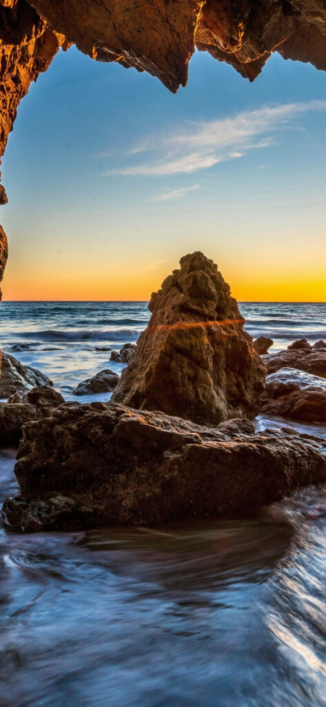 Coastal Scenery: Serene Shallow Waters and Natural Rock Formation at Malibu Beach Wallpaper