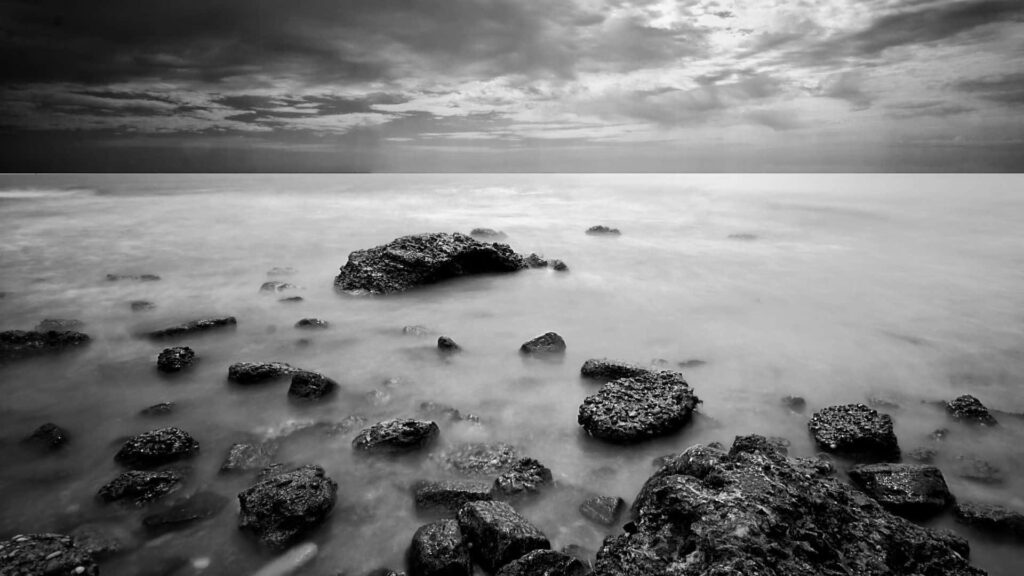 Serene Black and White Seascape: Tranquil Misty Waters and Rocks Wallpaper