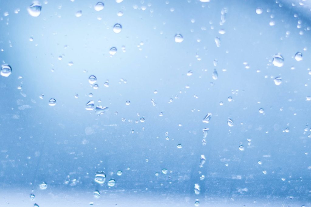 Macro shot of clear water droplets on wet blue glass minimalist wallpaper background banner