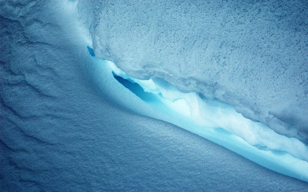 Serene blue and white ice cave with textured formations lit by soft natural light wallpaper
