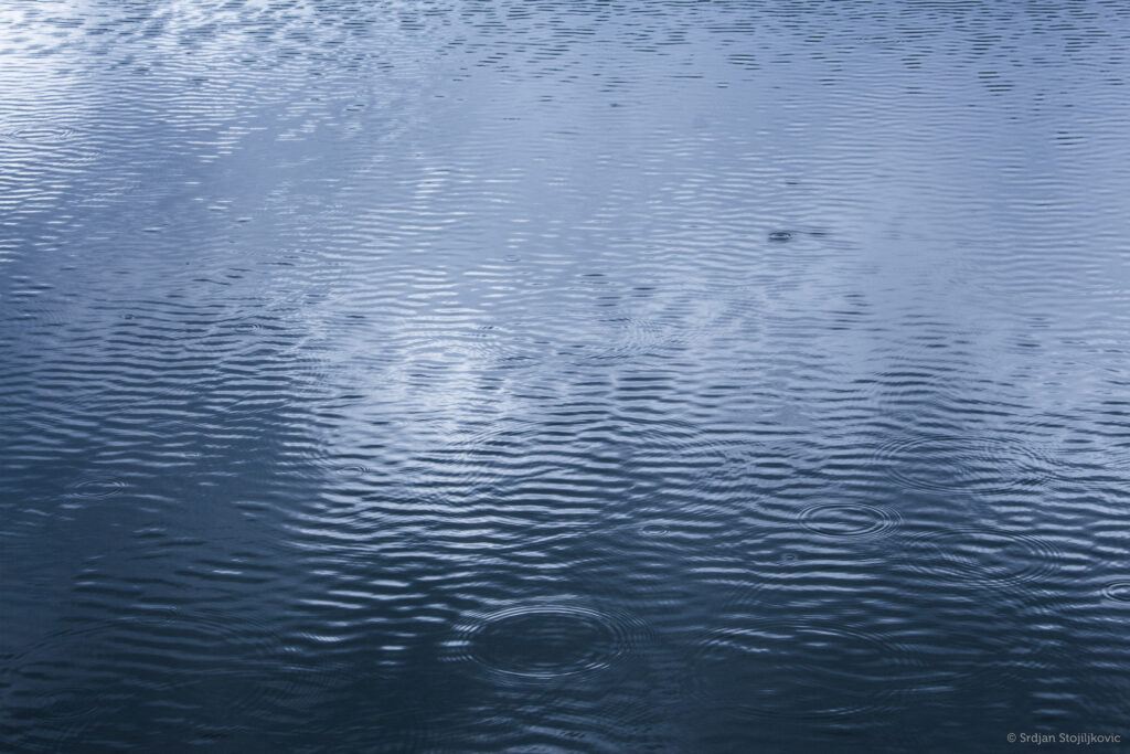 Serene lake surface with gentle ripples and blue reflections peaceful tranquil wallpaper background