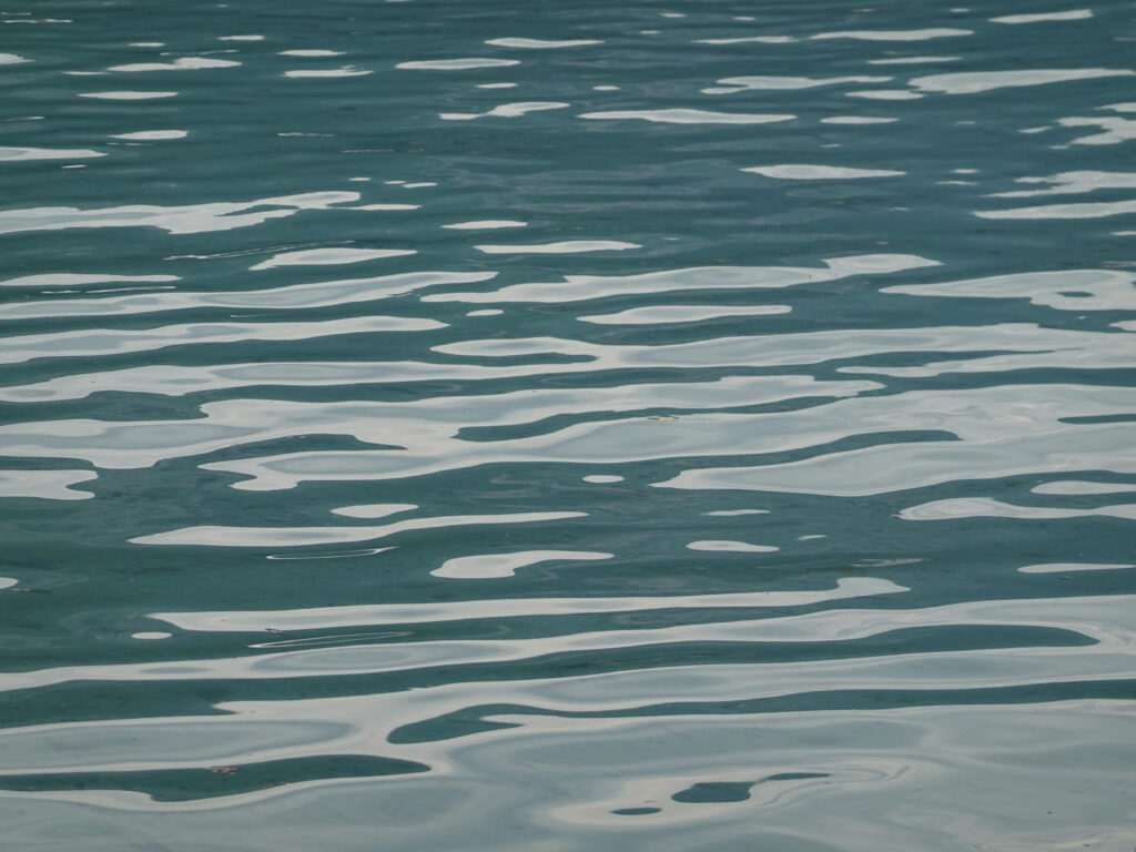 Serene blue water surface with gentle river ripples and soft natural light for peaceful wallpaper