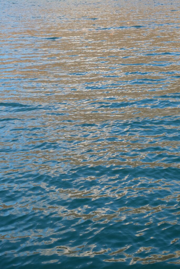 Serene sea wallpaper with soft blue ripples reflecting sunlight calming water texture background