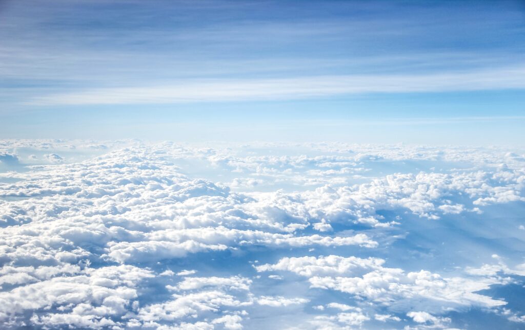 Panoramic wallpaper of fluffy white clouds across a blue sky creating a peaceful background