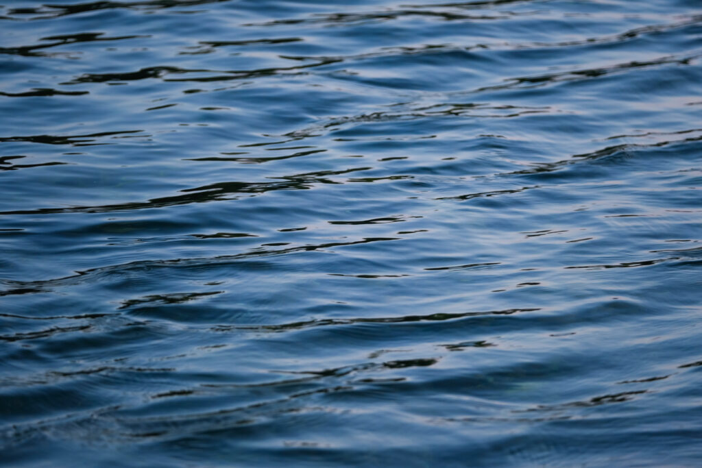 Tranquil blue water wallpaper with gentle waves and natural light reflections background