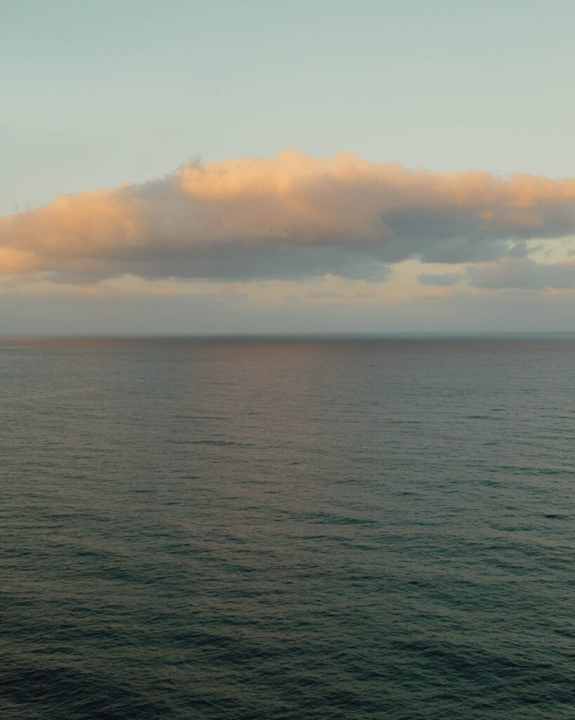 Calm sea with gentle ripples under pastel clouds serene wallpaper background for relaxation