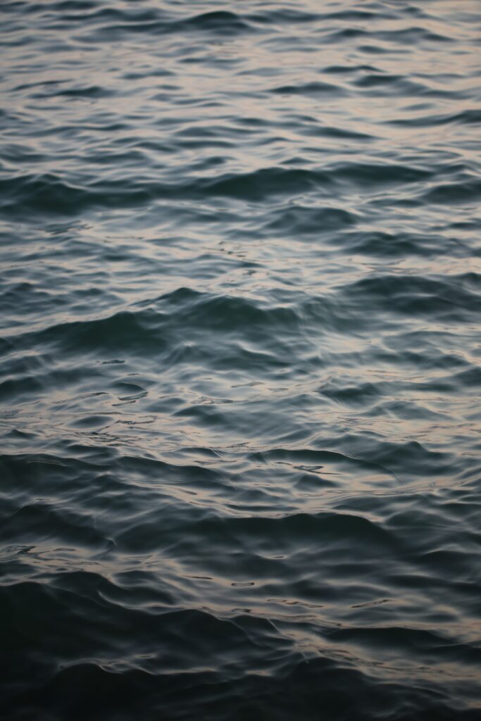 Calm water wallpaper with gentle ripples soft blue gray gradients and warm sunlight reflections