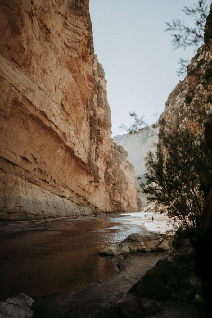 Stunning canyon with towering rock walls river and lush greenery under soft natural light wallpaper