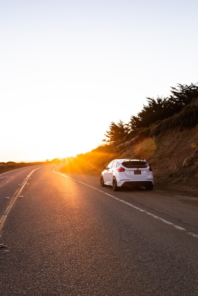 Serene Car Wallpaper: Rear View on Winding Road with Sunlit Landscape
