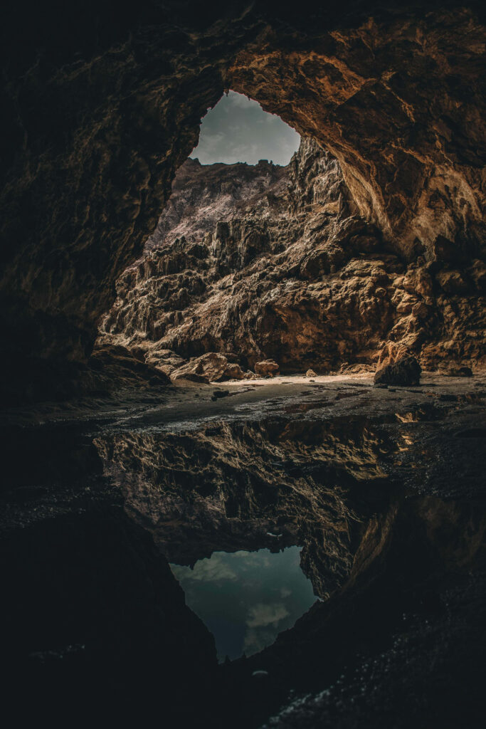 Tranquil Cave Wallpaper: Reflective Pool & Textured Walls Background