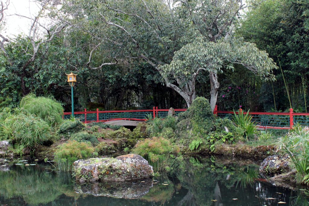 Tranquil Chinese pavilion with red bridge lantern pond lush greenery traditional garden wallpaper