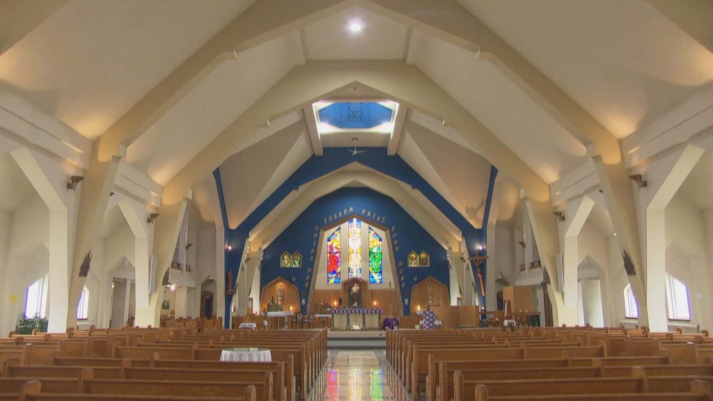 Serene church interior with wooden pews stained glass windows blue ceiling arch and white beams Wallpaper