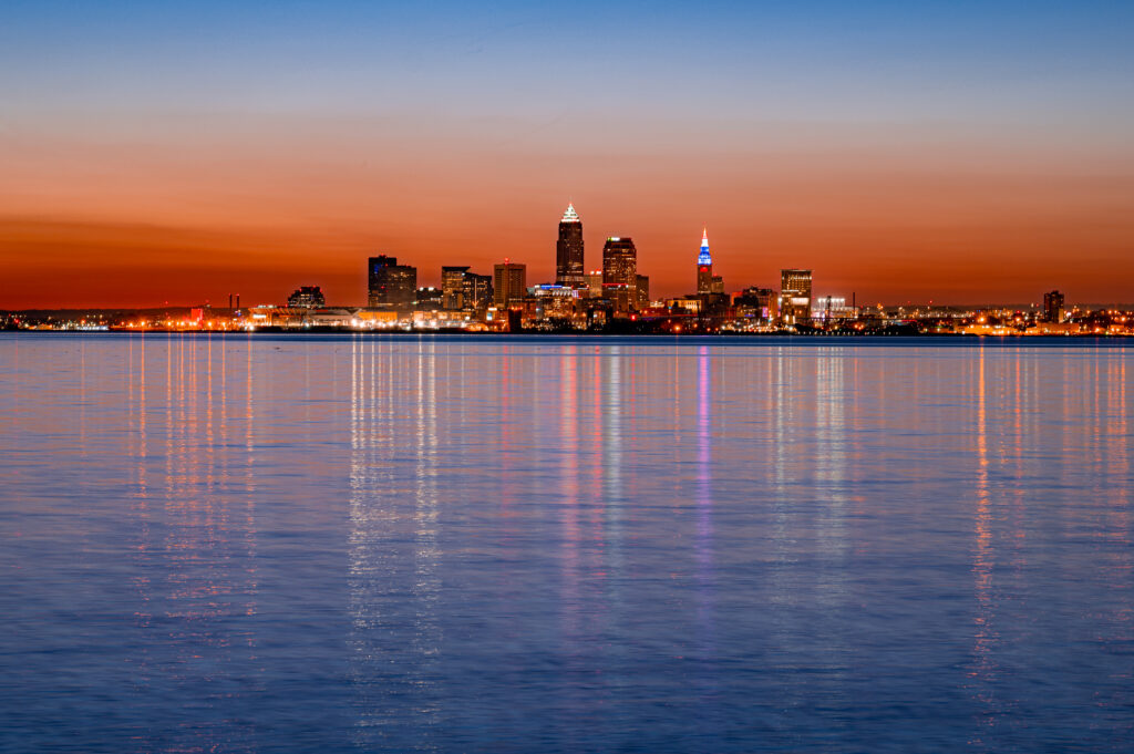 Serene Cityscape Sunset Wallpaper: Vibrant Reflections on Water