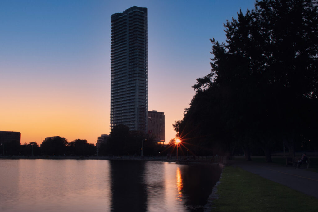 Serene Cityscape Sunset Wallpaper: Skyscraper & Calm Pond
