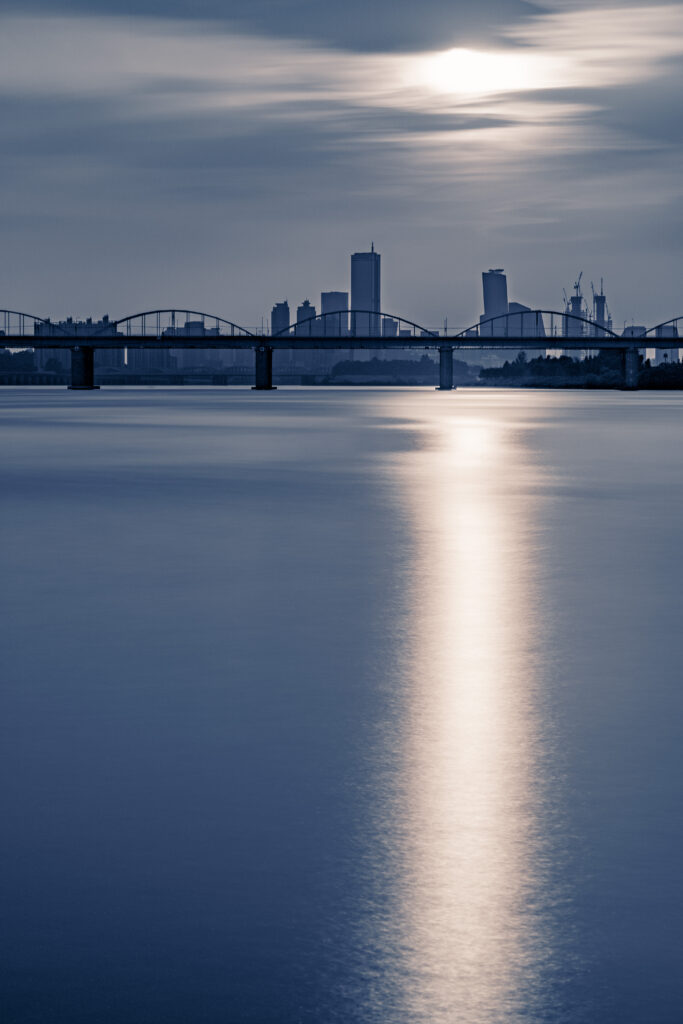 Tranquil Cityscape Wallpaper: Sunset Reflections & Silhouetted Bridge