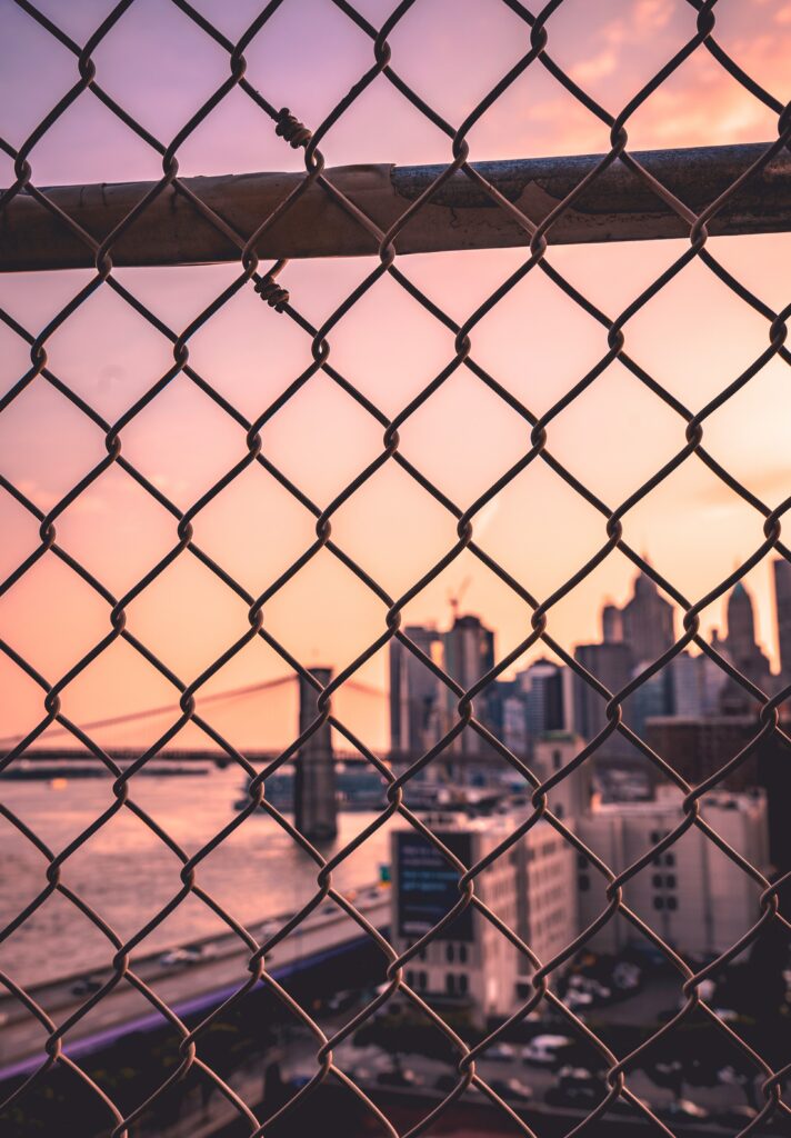 Serene Cityscape Wallpaper: Chain-Link Fence Sunset View
