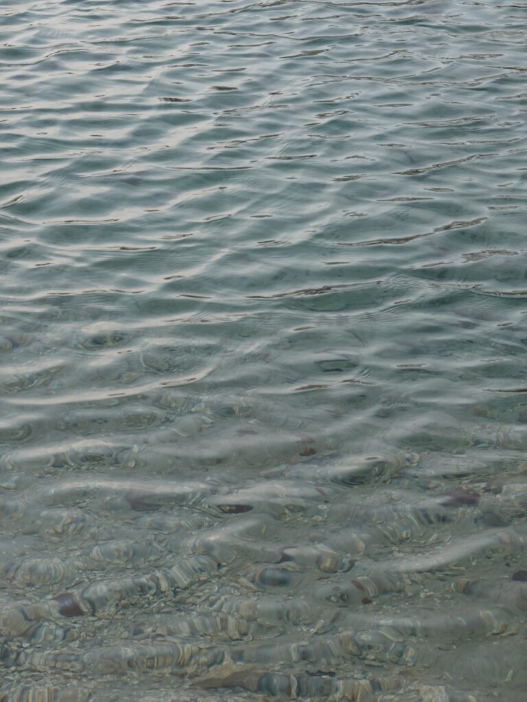 Clear river with gentle ripples revealing smooth pebbles in blue and gray serene water wallpaper