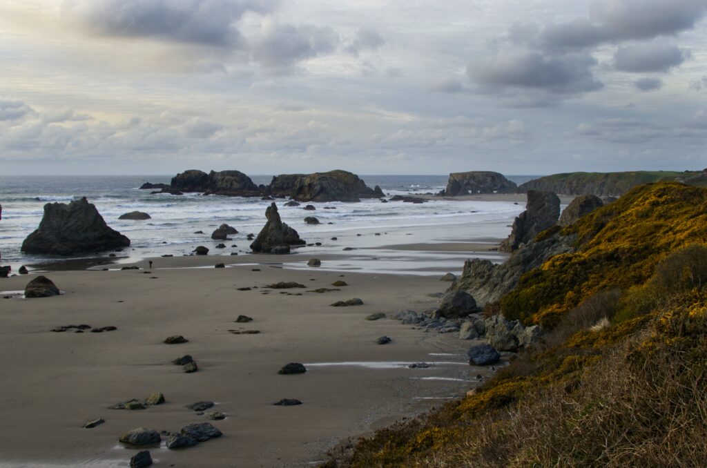 Tranquil beach wallpaper with rugged coastal rocks gentle sea waves and cloudy sky background