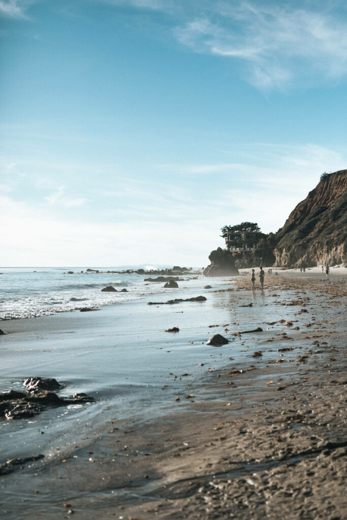 Awe-Inspiring Coastal Beauty Captured: Majestic Malibu Beach with Distanced Silhouettes Wallpaper