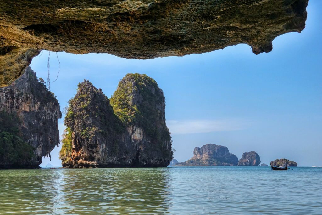 Serene coastal cliffs with rocky formations lush greenery calm sea and natural rock overhang wallpaper