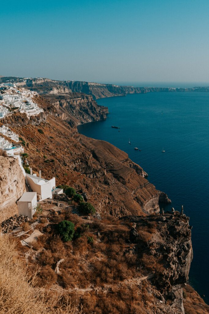 Coastal cliffs with white buildings overlooking deep blue sea under clear sky wallpaper background