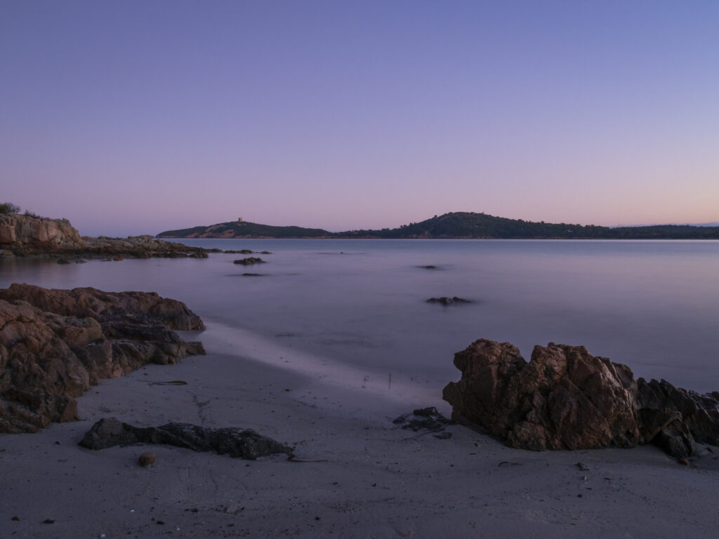 Serene coastal dusk wallpaper with calm sea rugged rocks islands purple pink sky background