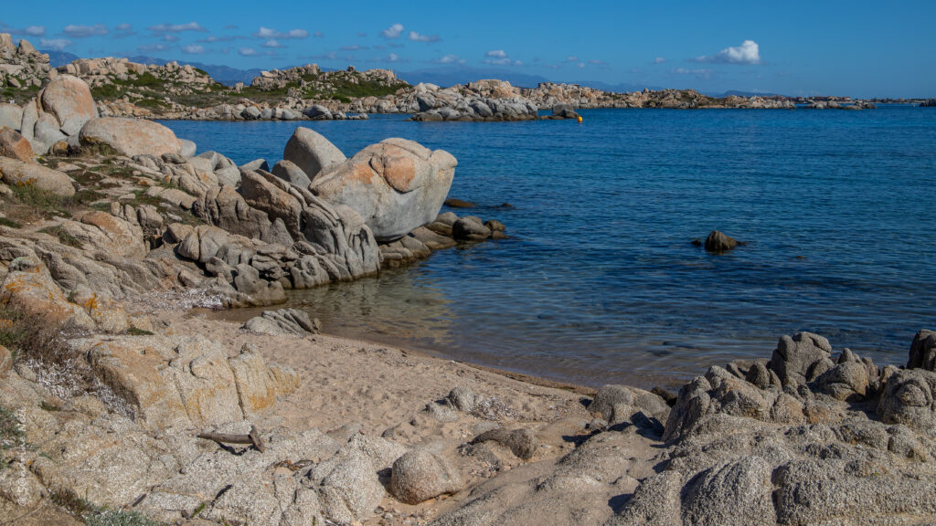 Serene coastal landscape with rugged rocks and calm blue sea under clear sky wallpaper background