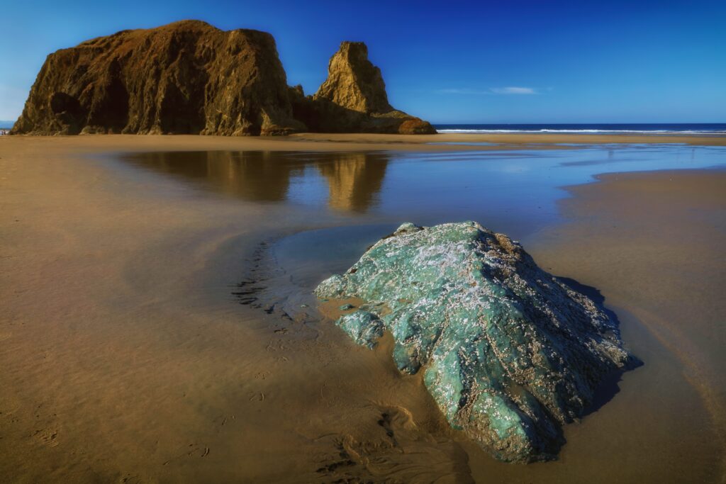 Serene coastal landscape with golden sand rugged rocks and tranquil blue sea under vivid sky Wallpaper