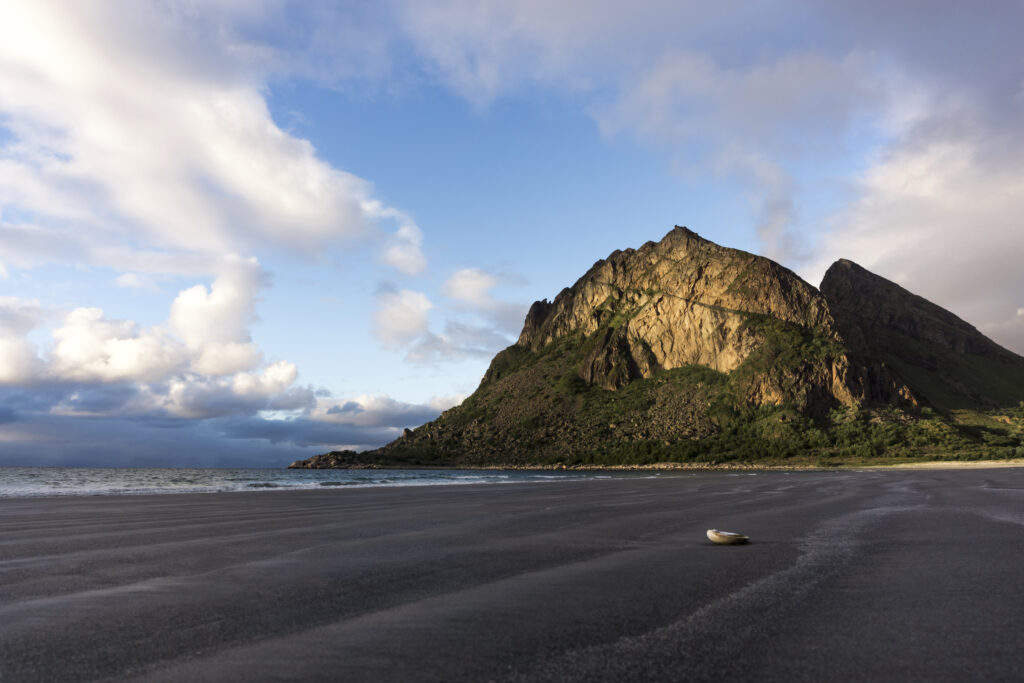Serene beach with dramatic rock formation turquoise water sandy shore and single shell wallpaper
