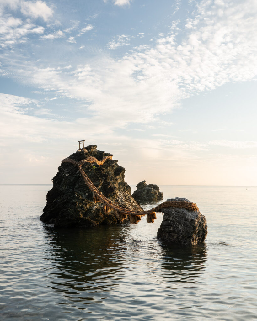 Serene coastal landscape with rope bridge between rocky formations over calm sea waters wallpaper