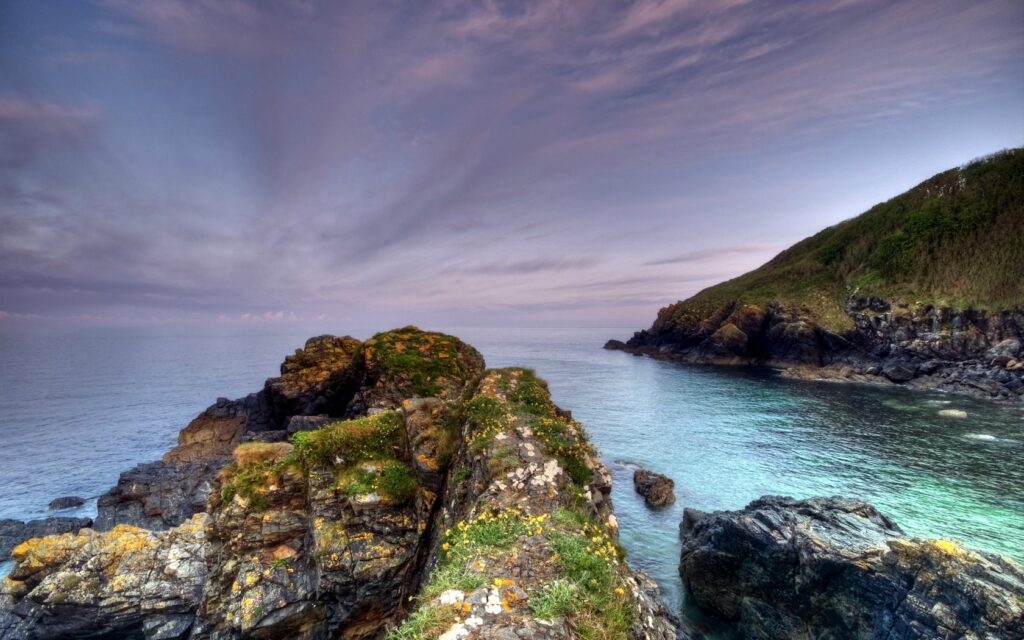 Serene coastal landscape with mossy rocks calm sea cloudy sky peaceful melancholy wallpaper background