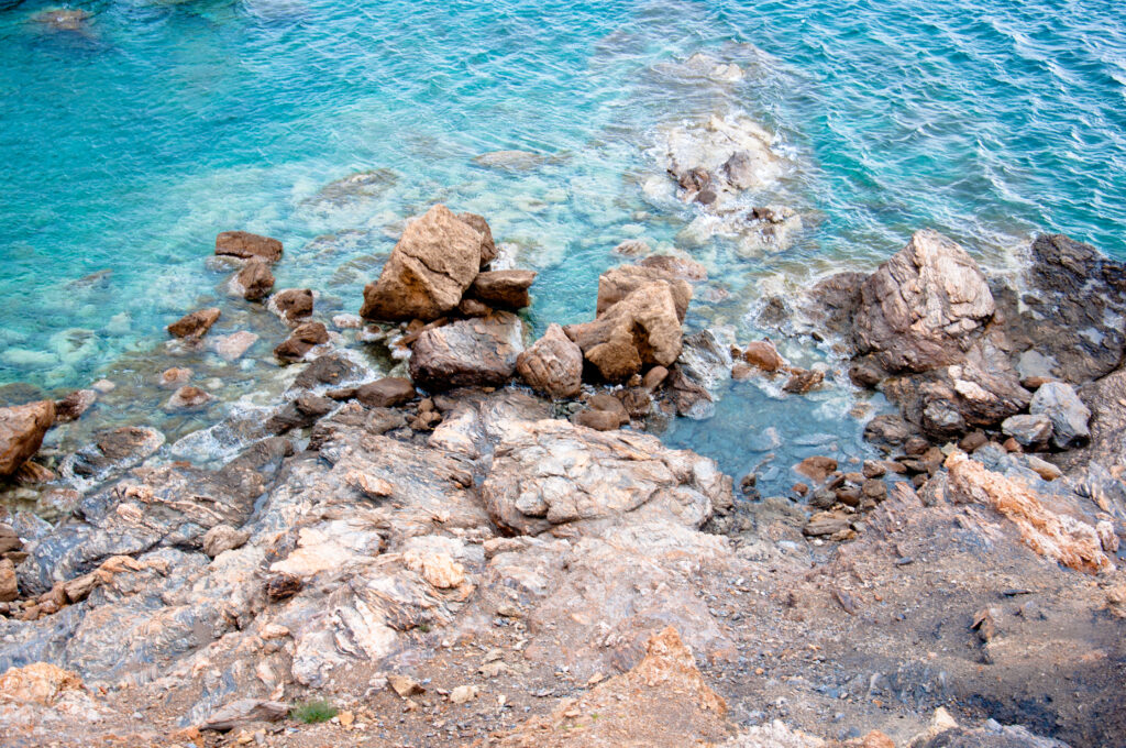 Serene coastal wallpaper with rugged stones and clear turquoise sea water flowing gently