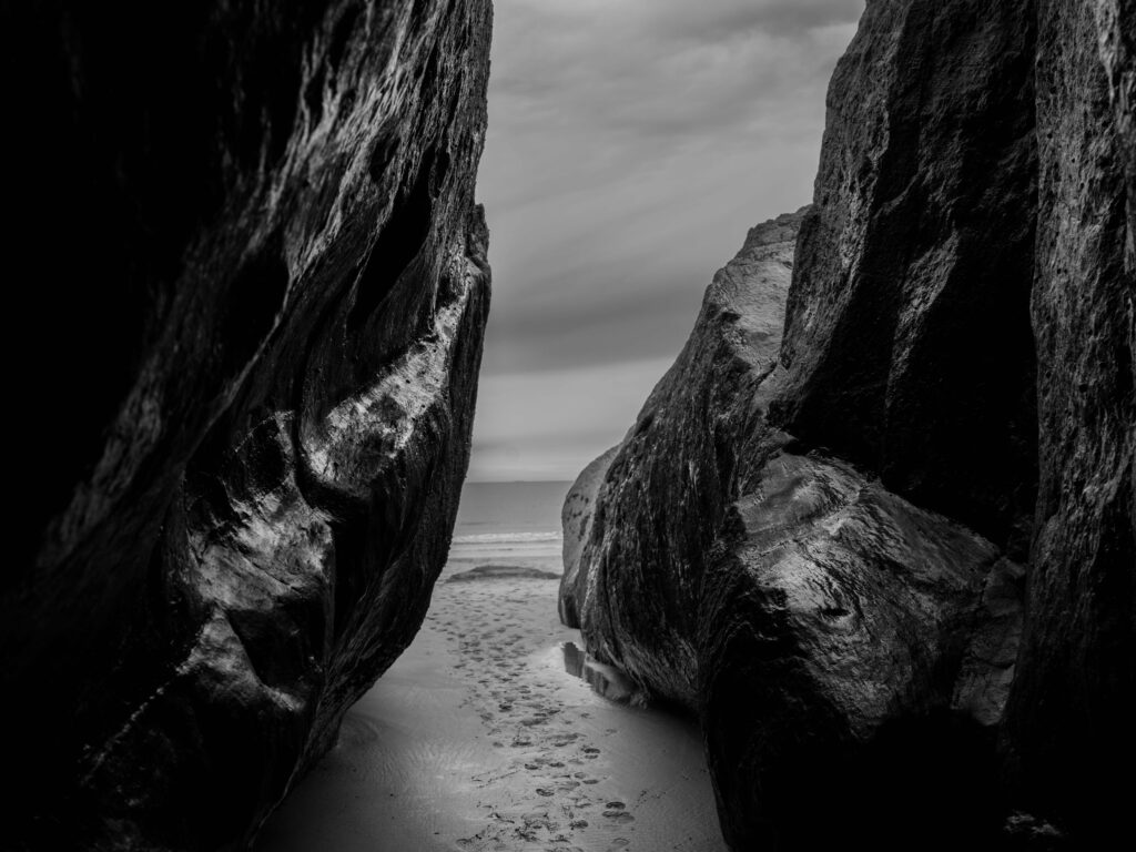 Serene Black and White Coastal Wallpaper with Footprints and Rocks