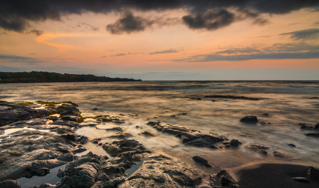 Serene coastal sunset with rugged stones misty sea fog pastel sky wallpaper background