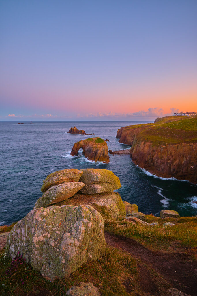 Sunset coastal scene with rugged rocks deep blue sea and cliffs under pastel sky wallpaper background