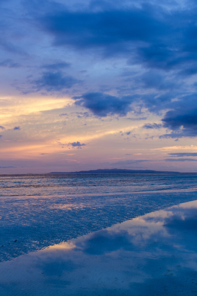 Serene coastal sunset wallpaper with gentle sea ripples and soft clouds in vibrant colors