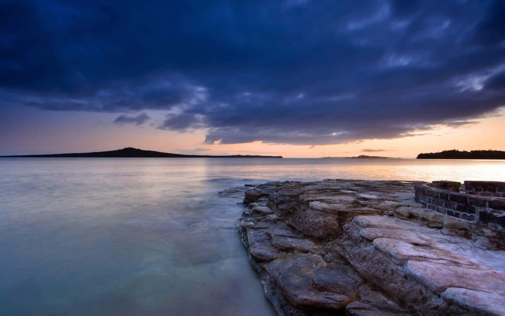 Tranquil Twilight Coastal Scene with Smooth Rocks and Sunset Hues Wallpaper