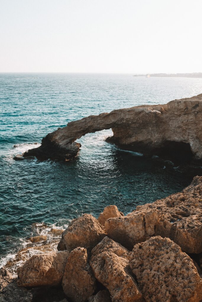 Serene coastal wallpaper with rocky foreground turquoise waves and dramatic natural stone arch
