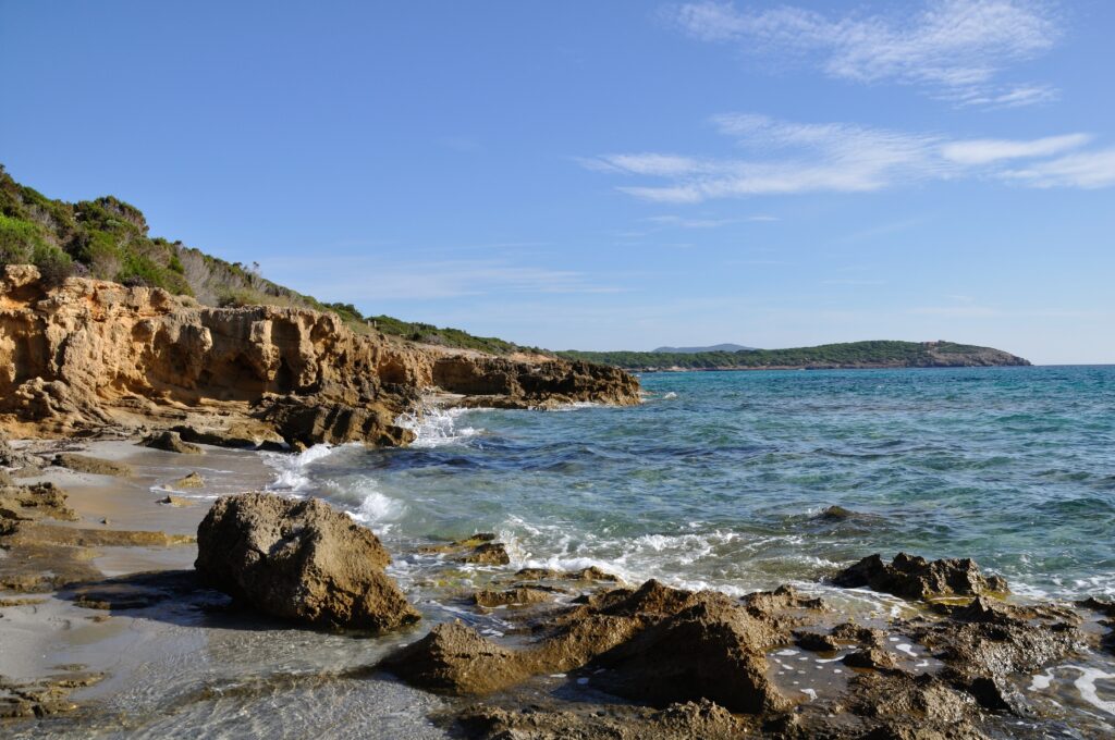 Serene coastal wallpaper with golden cliffs clear blue skies and gentle waves on rugged rocks
