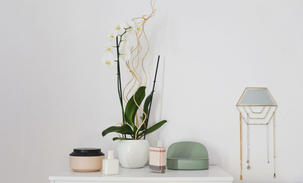A Serene Sanctuary: Captivating White Home Corner Enhanced with Delicate Orchid and Enchanting Ceramic Decor Wallpaper