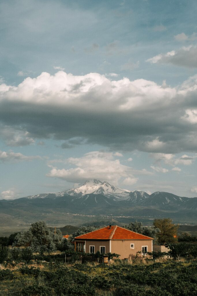 Tranquil Countryside Wallpaper: Cozy House & Snow-Capped Mountains