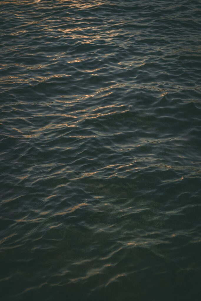 Serene deep blue sea surface with gentle ripples and moody soft lighting wallpaper background
